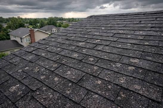 Roofer marking hail impact marks on shingles during a hail damage roof inspection