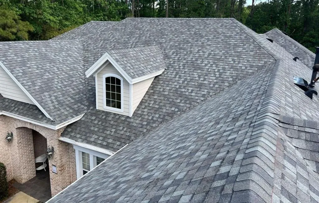 Close-up of hail damage on shingles showing dark impact marks and granule loss on an asphalt roof